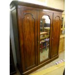 A 6' Victorian mahogany triple wardrobe with rounded moulded cornice, central mirror panel door