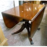 A reproduction mahogany and cross banded drop-leaf dining table, set on turned pillar and