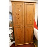 A 35" modern polished pine wardrobe with hanging space enclosed by a pair of panelled doors, set