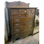 A 3' 4" early 20th Century oak serpentine front tallboy with shaped and moulded raised back, two