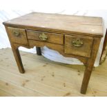 A 3' 3" antique oak lowboy with central drawer, flanking deep drawers and shaped apron, set on