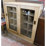 A 3' 6" waxed pine cabinet with pigeonhole fitted interior enclosed by a pair of glazed panel