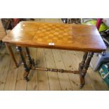 A 31" Victorian walnut and stained wood games table, set on twin flanking turned pillars and uniting