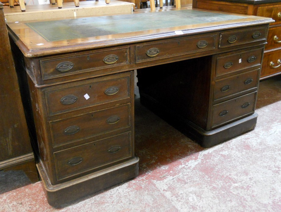 A 4' 6" early 20th Century mahogany twin pedestal desk with green leather inset top, three frieze