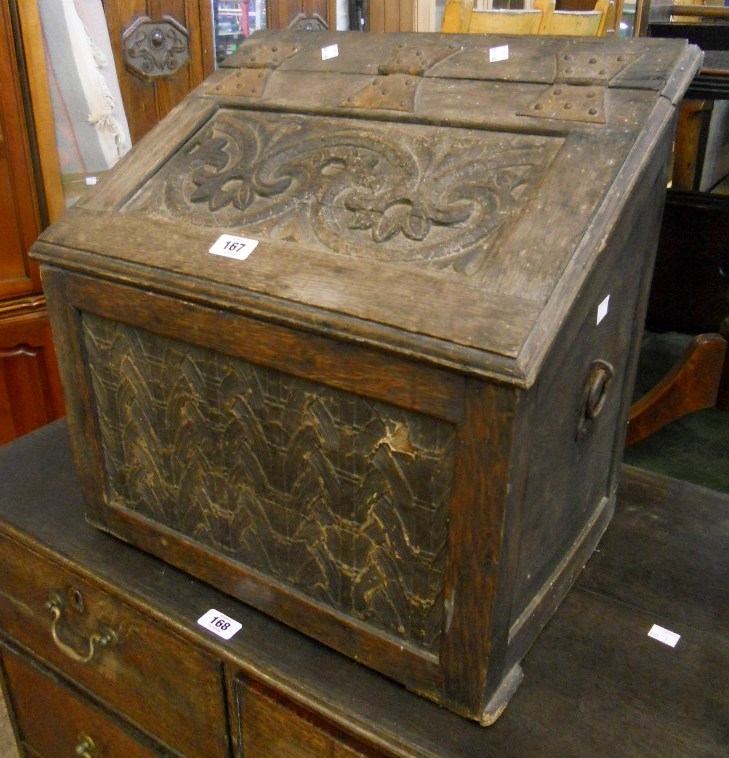 A 19" antique carved oak slope fronted coal box with decorative panels and flanking iron ring