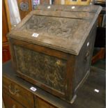 A 19" antique carved oak slope fronted coal box with decorative panels and flanking iron ring