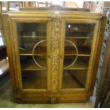 A 3' 6" mid 20th Century light oak display cabinet with carved floral decoration, set on a shaped