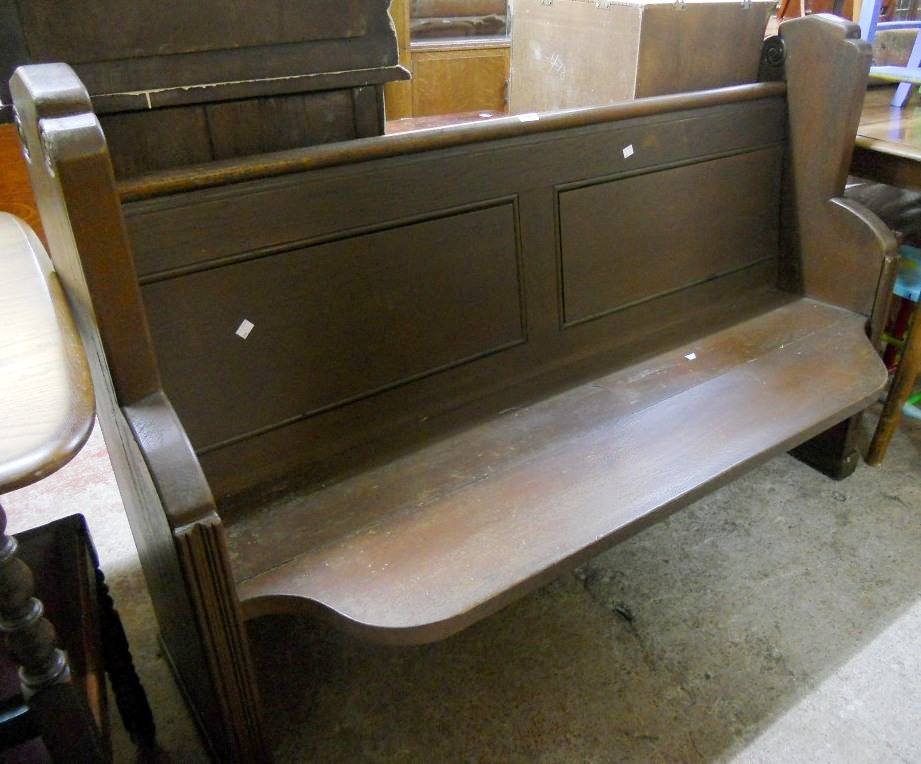 A 4' 10" stained oak pew with shaped and moulded ends, panelled back and solid seat