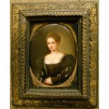 An antique ebonised and gilt framed oval portrait miniature on porcelain panel, depicting a young