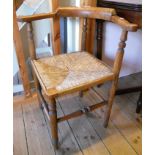 A stained beech corner chair with rush seat, set on turned supports and stretcher