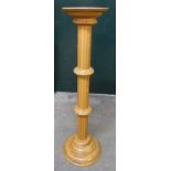 A light polished oak pedestal with fluted decoration and stepped circular base