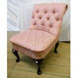 A reproduction button back nursing chair with pink floral upholstery, set on polished wood