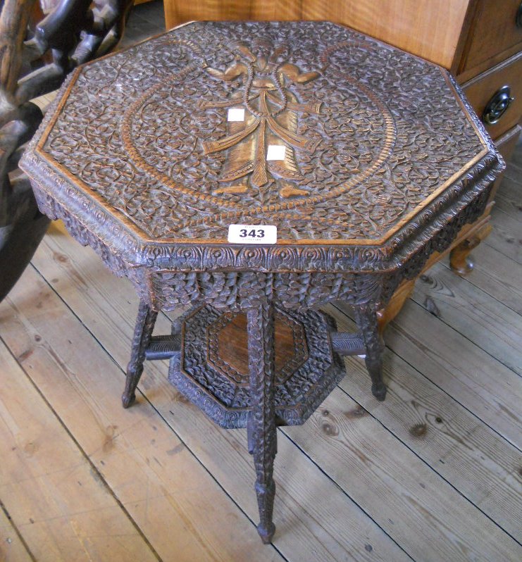A 18½" Anglo-Indian carved hardwood octagonal two tier occasional table with three headed male deity