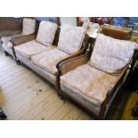 A 1930's stained walnut framed three piece bergere suite with fitted cushions and shaped armrests,