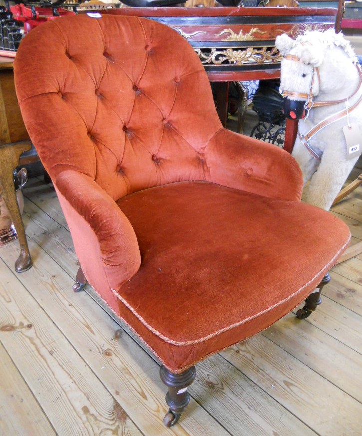 A Victorian drawing room armchair with copper coloured button back upholstery, set on turned front
