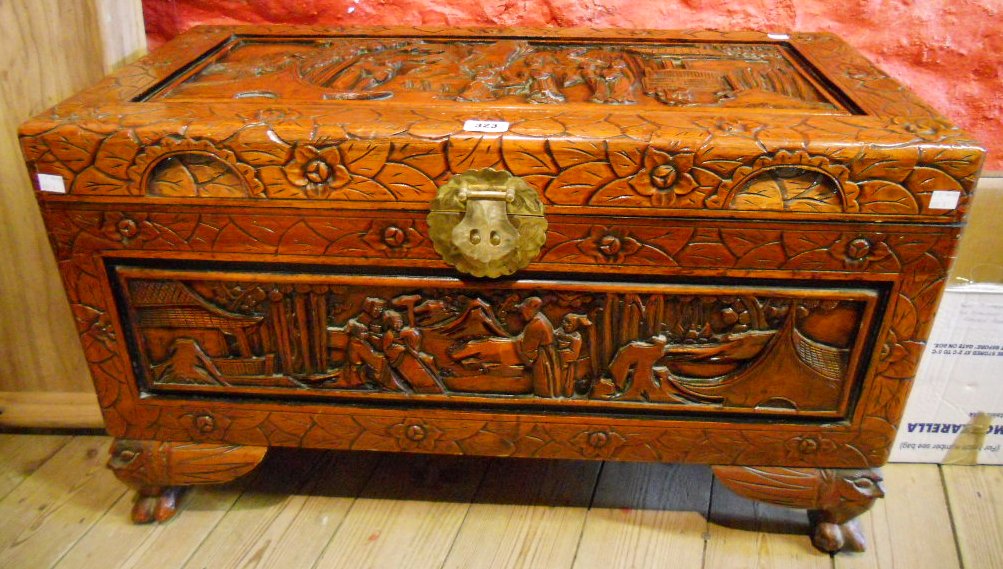 A 35" Oriental camphor wood chest with all over carved decoration, featuring figures in garden