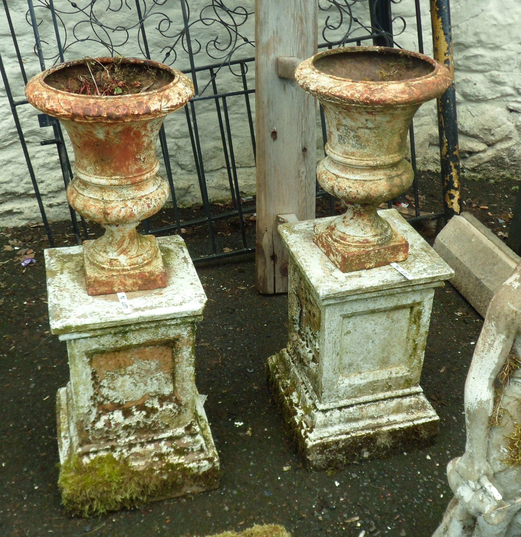 A pair of 16" Victorian cast iron urns, set on 19" terracotta pedestals