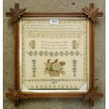 A Victorian ornate oak framed alphabet, verse and floral decorated sampler by Catherine Hannah Payne