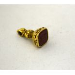 A SMALL GOLD COLOURED FOB, with carnelion hardstone detail to the base, engraved