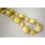 AN IVORY NECKLACE, comprising of oval and oblong beads, largest bead measures 30mm x 20mm, length