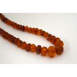 A STRAND OF FACETED AMBER COLOURED BEADS, length 48cm