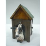 A CROWN DEVON MUSICAL AUTOMATED CIGARETTE DISPENSER, modelled as a dog in a kennel, with