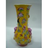 AN ORIENTAL VASE, yellow ground embossed with a pair of mask heads and household objects, height