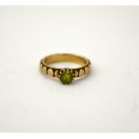 A 9CT GOLD PERIDOT RING, with single circular pendant to the fancy bi-metal coloured band, hallmarks