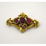 AN EARLY 20TH CENTURY BROOCH, with three oval red coloured paste stones with fancy scrolling