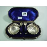 A PAIR OF CASED SILVER OPEN SHELL SALTS, on three ball feet with matching spoons, Birmingham 1894