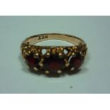 A GARNET RING, with three circular shape garnets to the textured tapered shank, stamped 9ct, ring