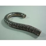 A VINTAGE WHITE METAL PARASOL HANDLE, the curved form with floral and leaf embossed decoration,