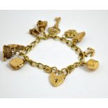 A 9CT GOLD CHARM BRACELET, comprising of ten novelty charms to the curb link chain and heart shape