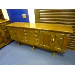 AN OAK SIDEBOARD, on stretchered legs with central bank of drawers