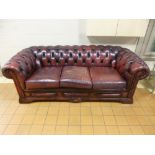 A LEATHER BURGUNDY THREE SEATHER CHESTERFIELD (well worn and ripped)