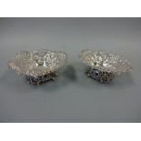 A PAIR OF PIERCED SILVER BON BON DISHES, with bow and floral decoration on four shaped bracket feet,