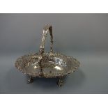 AN OVAL SILVER PIERCED BASKET, with swing handle with mask head mounts, scroll shell and figural