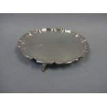 A SILVER SALVER, of shaped circular form with pie crust rim set on three hoof feet, Sheffield