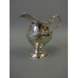 A SILVER MILK JUG, of urn form with repousse floral and leaf decoration, vacant cartouches, beaded