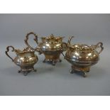 A SILVER THREE PIECE TEA SERVICE, of waisted form with shaped tops set on scroll feet, teapot