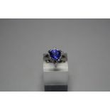 AN 18CT GOLD TANZANITE AND DIAMOND RING, with trillian cut tanzanite to a surround of brilliant