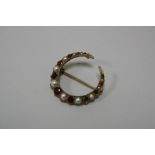 AN EDWARDIAN BROOCH, designed as a crescent moon with alternate pearl and garnet detail, stamped .