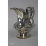 A SILVER EWER, of shaped baluster form on circular foot with engraved vine, leaf and scroll