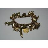 A 9CT GOLD CHARM BRACELET, comprising of nineteen novelty charms to include a half sovereign to