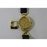 A LADIES GUCCI WRISTWATCH, with circular facet, gold plated dial with black leather strap (strap