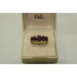 A 9CT GOLD GARNET RING, with five oval shape graduated garnets to the fancy tapered shank, hallmarks