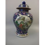 AN ORIENTAL OVOID VASE AND COVER, cartouches decorated with landscape scenes to blue ground with