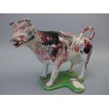 A 19TH CENTURY STAFFORDSHIRE COW CREAMER AND COVER, sponge decorated with pink and black spots, on