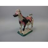 A 19TH CENTURY STAFFORDSHIRE PEARLWARE COW CREAMER, sponge decorated in pink and black on canted