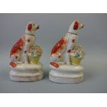 A NEAR PAIR OF 19TH CENTURY STAFFORDSHIRE SEATED SPANIELS, with gilt collars and basket of